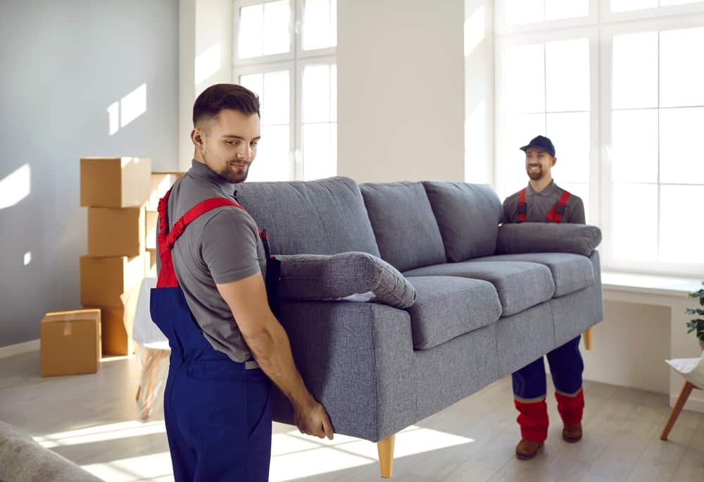 two movers carrying couch.